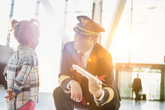 肖像成熟的飞行员持有飞机玩具玩可爱的女孩机场