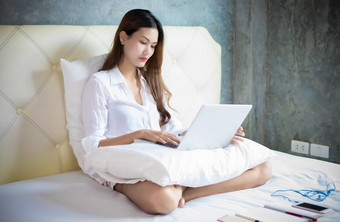 亚洲女人笔记本电脑工作首页坐着床上检疫冠状病毒疫情