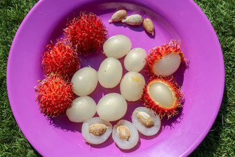 关闭红毛丹去皮水果前视图健康的水果紫色的背景准备好了吃甜蜜的巴厘岛水果水果圆形的椭圆形single-seeded浆果覆盖肉质柔软刺