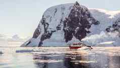 红色的巡航汽船漂流冰山巨大的岩石