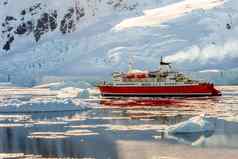 红色的巡航汽船漂流冰山巨大的岩石