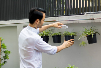 年轻的但<strong>浇水</strong>植物盆栽植物可回收的塑料瓶<strong>浇水</strong>植物扭曲的塑料瓶回收年轻的男人。工作花园