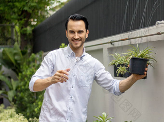 年轻的但浇水植物盆栽植物可回收的塑料瓶浇水植物扭曲的塑料瓶回收年轻的男人。工作花园