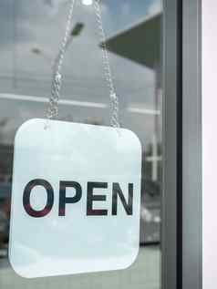 白色开放标志挂玻璃通过咖啡商店