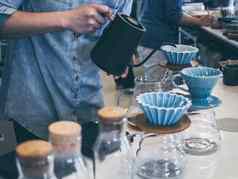 咖啡师蓝色的衬衫倒热水黑色的水壶