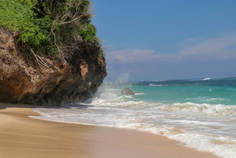 海滩山伞海滩细金沙子巴厘岛绿<strong>松石</strong>蓝色的水转海泡沫波打破岩石悬崖海岸阳光明媚的一天蓝色的天空旅游自然概念