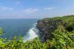 视图Uluwatu悬崖展馆蓝色的海巴厘岛印尼美丽的风景普拉崇高Uluwatu寺庙色彩斑斓的花前景一天风景优美的沿海景观高悬崖