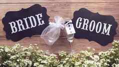 香槟玻璃婚礼衣服新娘新郎文本标志木背景装饰小白色花古董风格婚礼标志概念
