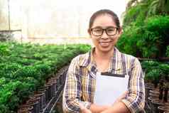 亚洲园丁女人站平板电脑幼苗托儿所微笑相机技术农业概念
