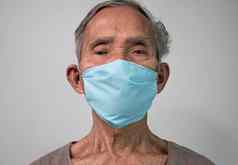 肖像亚洲高级但穿面部面具保护空气污染病毒疫情灰色背景健康护理概念