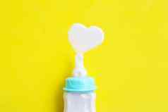 瓶牛奶婴儿黄色的背景牛奶心形状