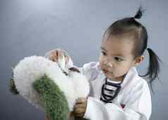 亚洲女孩角色玩医生占领穿白色礼服统一的滴眼睛豪华的玩具熊玩学习孩子们