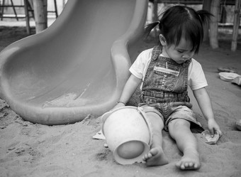 亚洲女孩坐着沙子地面操场上玩沙子塑料海滩玩具幸福的玩学习孩子们黑白图片
