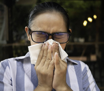 亚洲年轻的女人华林眼镜持有组织吹鼻子流鼻涕的鼻子流感季节健康医疗概念
