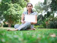 亚洲年轻的女人持有空白白板疼痛肩膀坐着草地面公园空间文本