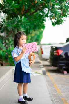 亚洲女孩泰国学校统一的持有礼物盒子