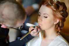 年轻的美丽的新娘应用婚礼化妆