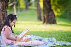 可爱的女孩阅读书坐着树