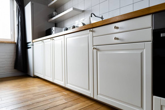 电器家具明亮的白色橱柜木工作台面电炊具感应滚刀水龙头水槽菜架硬木地板上光瓷砖现代斯堪的那维亚厨房