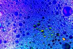色彩斑斓的滴石油水蓝色的紫色的彩色的圈椭圆摘要背景设计
