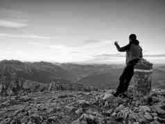 徒步旅行者需要自拍照片男人。坐奥地利德国边境石头高山山