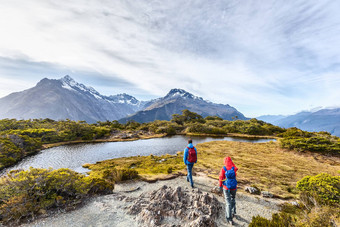 徒步旅行夫妇走冒险徒步旅行路特本跟踪阳光明媚的一天徒步旅行者携带背包踩关键峰会跟踪人假期峡湾国家公园新西兰