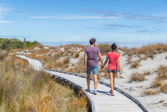 夫妇走海滩持有手浪漫的新西兰年轻的人船溪西海岸新西兰旅游夫妇观光南岛新西兰