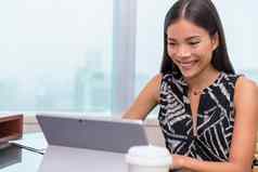 亚洲女人微笑移动PC屏幕视频闲谈，聊天会议在线工作办公室桌子上自由工作首页客户服务支持
