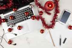 平躺电脑工作圣诞节假期前视图光木表格铝移动PC开放红色的装饰红色的装饰物智能手机基斯蜡烛块笔记耳朵豆荚铅笔笔