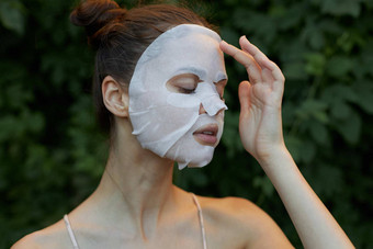 美丽的女人抗皱面具关闭眼睛透明的纸皮肤护理叶子背景