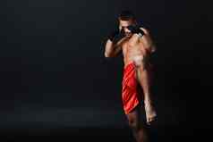 运动员泰拳泰国男人。拳击手的立场膝盖踢黑色的背景