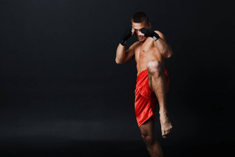 运动员泰拳泰国男人。拳击手的立场膝盖踢黑色的背景