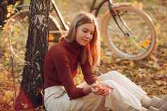 快乐活跃的年轻的女人坐着古董自行车秋天公园日落