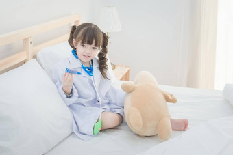 可爱的女孩享受玩医生医生玩具集可爱的娃娃坐着床上卧室首页