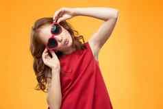 女孩黑色的眼镜红色的衣服童年有趣的黄色的背景