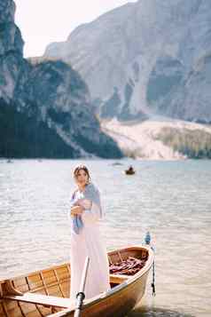 新娘站木船泻湖布雷斯意大利婚礼欧洲布雷斯湖年轻的女孩白色婚礼衣服涵盖了肩膀蓝色的毛衣