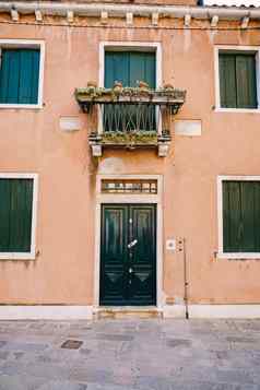 特写镜头建筑外墙威尼斯意大利两层楼的桃色的建筑绿色木百叶窗窗户通过阳台前面通过伪造的金属网格