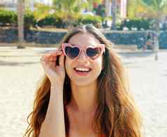 漂亮的浅黑肤色的女人女人粉红色的心洛丽塔太阳镜海滩假期假期旅行自由概念美丽的快乐女孩心形状的太阳镜海滩