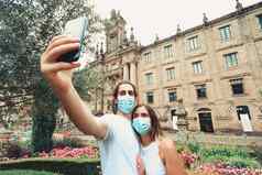 年轻的夫妇采取花俏的自拍面具花园前面建筑