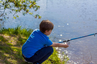男孩坐着海岸湖钓鱼杆钓鱼渔夫孩子钓鱼河