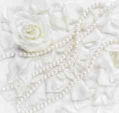 美丽的白色玫瑰花瓣珍珠项链白色背景理想的问候卡片婚礼生日情人节一天母亲的一天