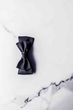 黑色的丝绸丝带弓大理石背景平铺