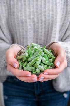 女手持有碗冻绿色豆子蔬菜保存收获纯素食主义素食者健康的吃
