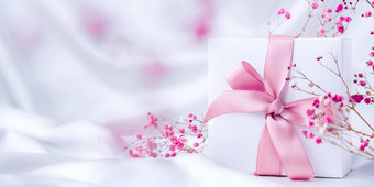 白色现在盒子粉红色的丝带小粉红色的花白色丝绸织物背景问候卡假期