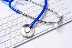蓝色的听诊器电脑键盘白色表格背景在线医疗信息治疗技术概念关闭宏复制空间