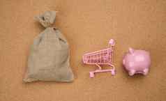 粉红色的陶瓷小猪银行微型购物车完整的帆布袋棕色（的）背景前视图
