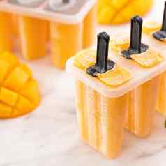 新鲜的芒果水果冰棒冰塑料塑造盒子明亮的大理石表格夏天情绪概念产品设计关闭