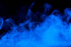 概念上的图像蓝色的烟孤立的黑暗黑色的背景木表格