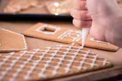 女人装修姜饼饼干房子白色结霜糖衣奶油一流的木表格背景烘焙纸厨房关闭宏