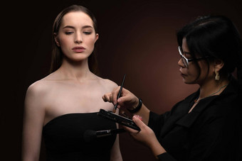 美化妆艺术家工作时尚模型漂亮的脸孤立的黑色的背景美丽的模型使艺术家化妆艺术家应用眼睛影子模型